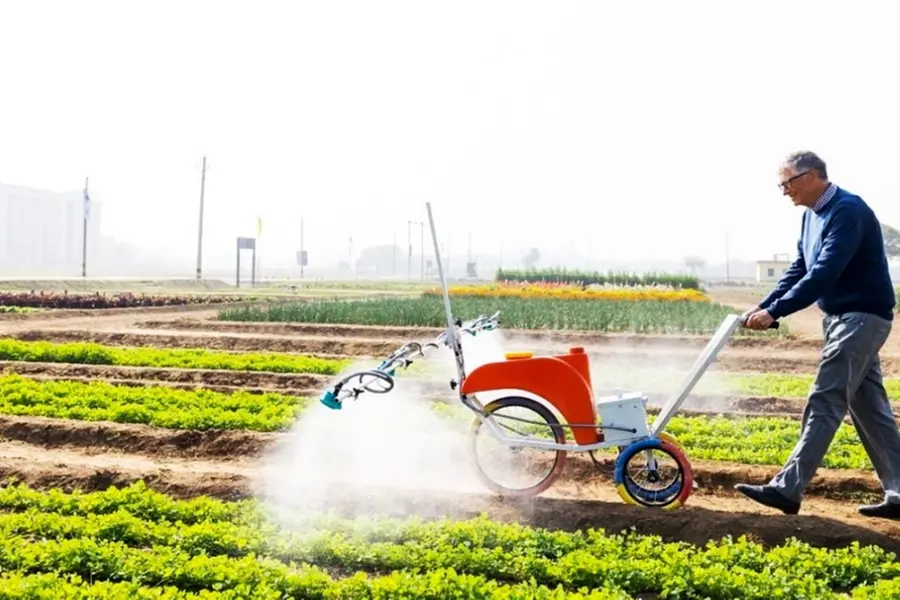 Why is Bill Gates trying a pesticide sprayer on Indian farmland?