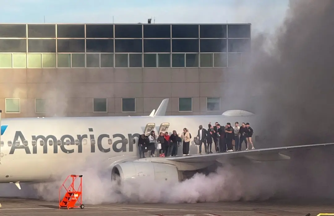 Passengers standing on the wing of an American Airlines plane as they are evacuated after it caught fire while at a gate at Denver International Airport | Photo: