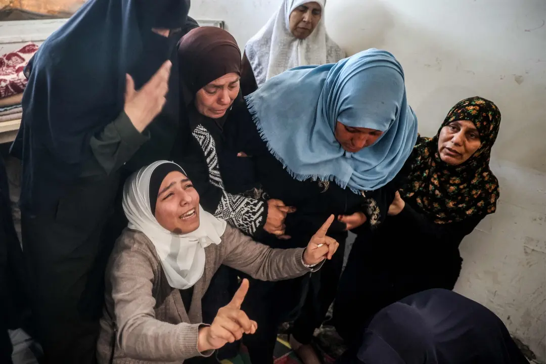 Women mourn by the body of one of the victims who were killed in Israeli bombardment | Photo: AFP