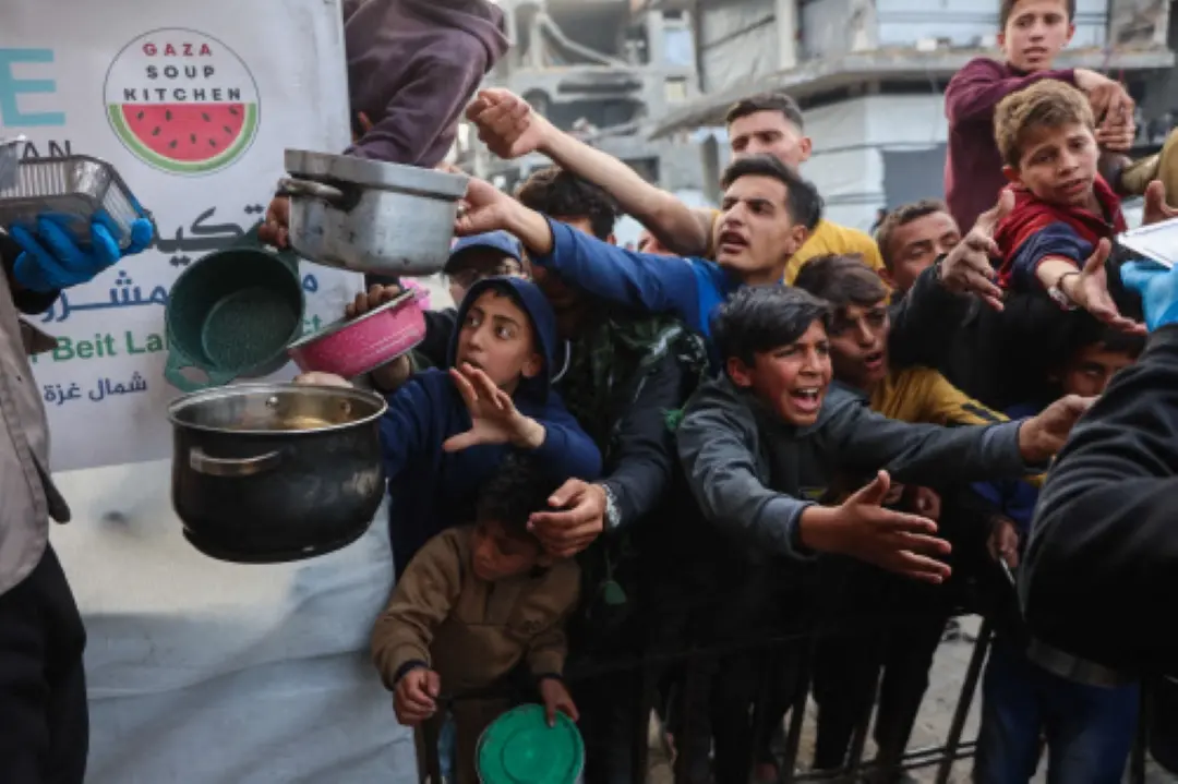 Displaced Palestinian children push into a queue to get a portion of cooked food from a charity kitchen in Beit Lahia in the northern Gaza Strip, ahead of the iftar fast-breaking meal during the Muslim holy month of Ramadan. | Photo: AFP