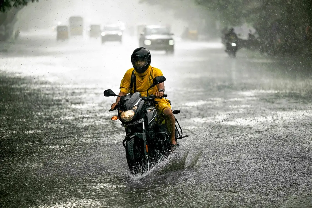 A commuter rides along a street during rainfall in Chennai | File photo: AFP