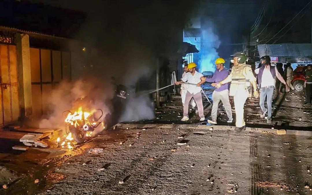 Police personnel try to douse a fire after clashes that broke out during a rally celebrating the Indian team's victory over New Zealand in the Champions Trophy final, in Mhow, Madhya Pradesh