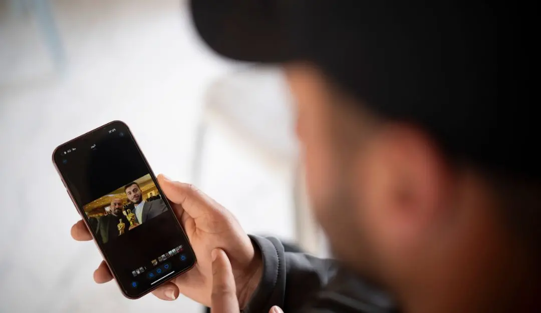 Salem Adra, shows a photo on his mobile phone in the West Bank village of Tuwani, depicting his brother, Palestinian activist Basel Adra, right, and Hamdan Ballal after they have been awarded Best Documentary Feature at the Oscars for 'No Other Land' | Photo: AP