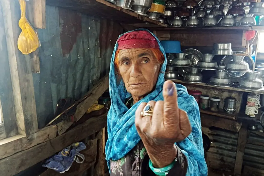 An elderly woman voter shows her finger marked with indelible ink after casting her vote through the postal ballot under the 'voting from home' facility for the Jammu and Kashmir Assembly elections, in Srinagar