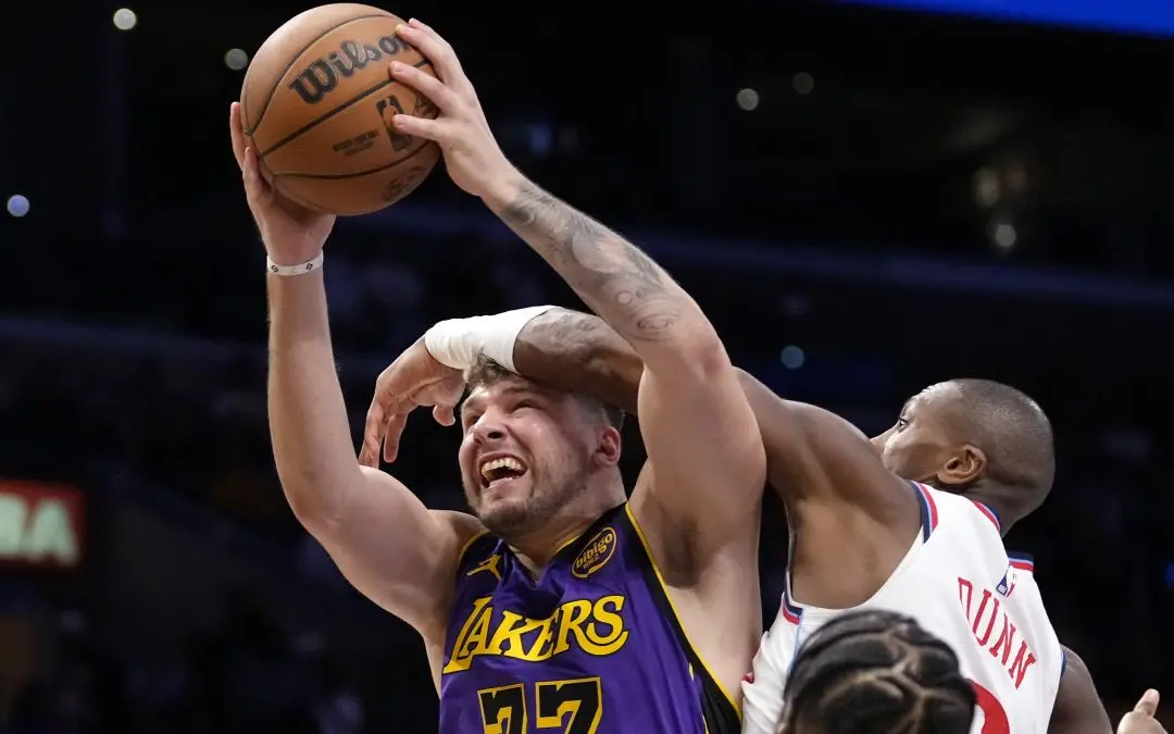 Los Angeles Lakers guard Luka Doncic, left, shoots as Los Angeles Clippers guard Kris Dunn defends during the second half of an NBA basketball game