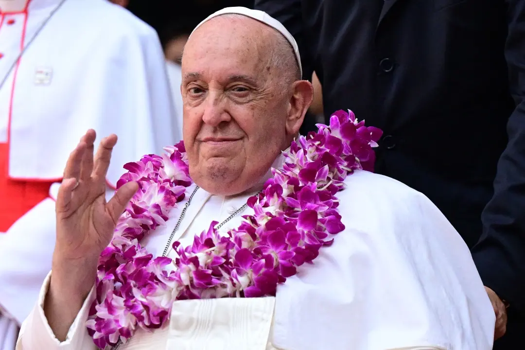 Pope Francis wears a flower garland as he arrives for an interreligious meeting with young people at the Catholic Junior College in Singapore