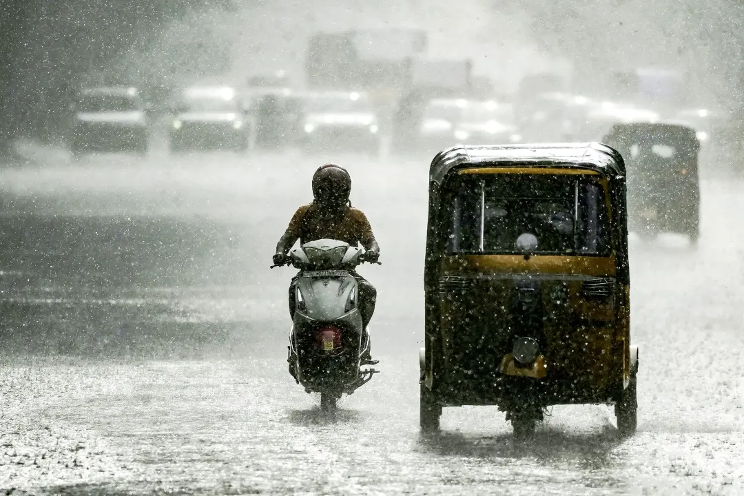 Commuters ride along a street during rainfall in Chennai | Photo: AFP