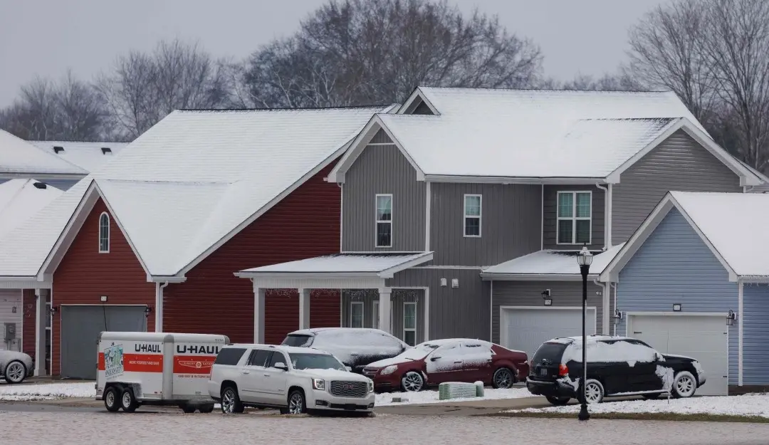 A vehicle makes its way through a flooded housing development after a rain storm