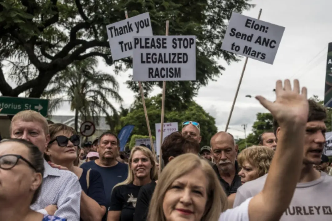 White South Africans supporting US President Donald Trump and South African and US tech billionaire Elon Musk gather in front of the US Embassy in Pretoria. | Photo: AP