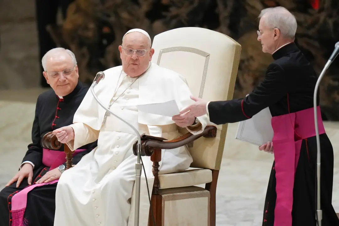 Pope Francis hands over his speech to Monsignor Luis Maria Rodrigo (r), to read, during his weekly general audience in the Paul VI Hall, Vatican | Photo: AP