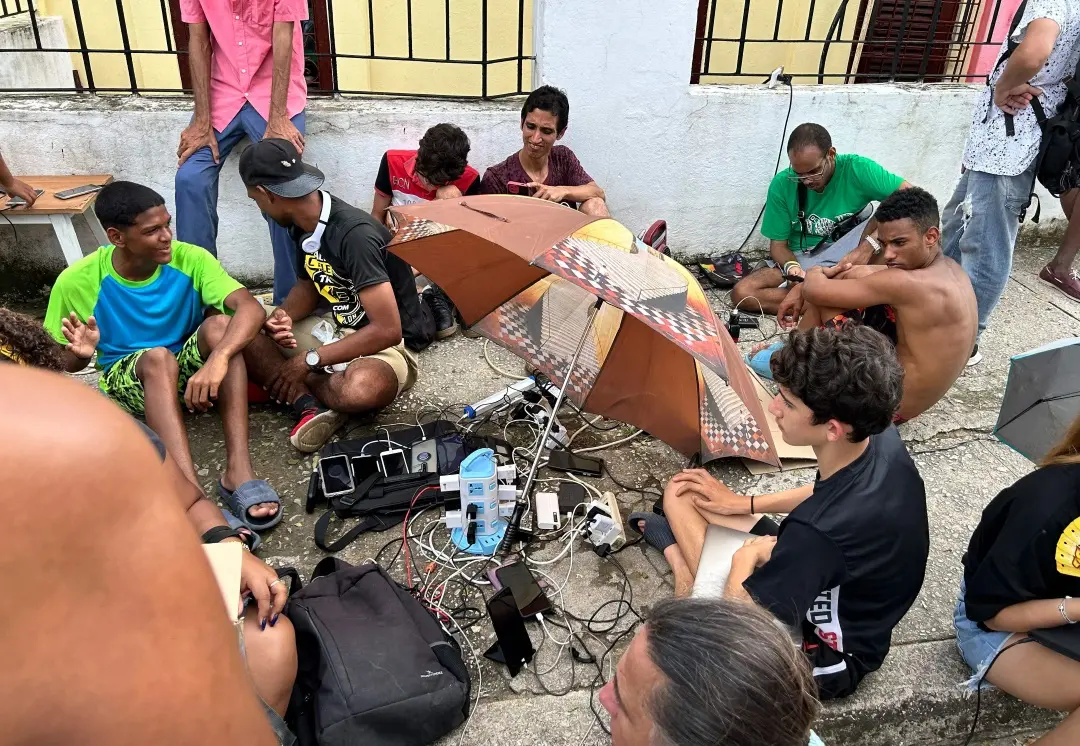 People charge their mobile phones in the aftermath of Hurricane Rafael, which affected the electricity service, near Havana