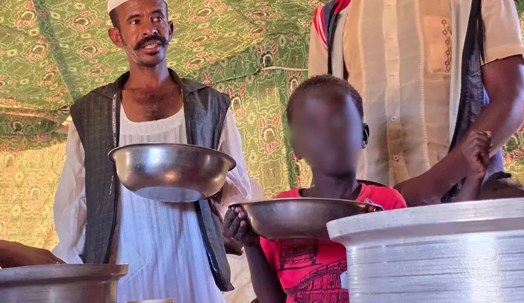 A child and a man wait to collect food at a location set up by a local humanitarian organisation to donate meals and medication to people displaced by the war in Sudan, in Meroe in the country's Northern State | File Photo: AFP