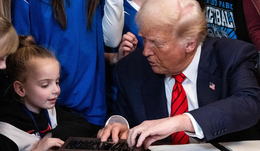 US President Donald Trump speaks with a little girl as he selects a pen to sign the No Men in Women's Sports Executive Order in the East Room of the White House in Washington, DC | Photo: AFP