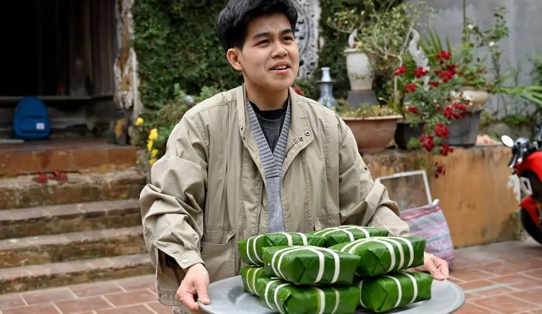 Nguyen Dao Anh Khoi carrying wrapped banh chung rice cakes, a traditional Vietnamese lunar new year or Tet festival delicacy, at his house in Hanoi | Photo: AFP