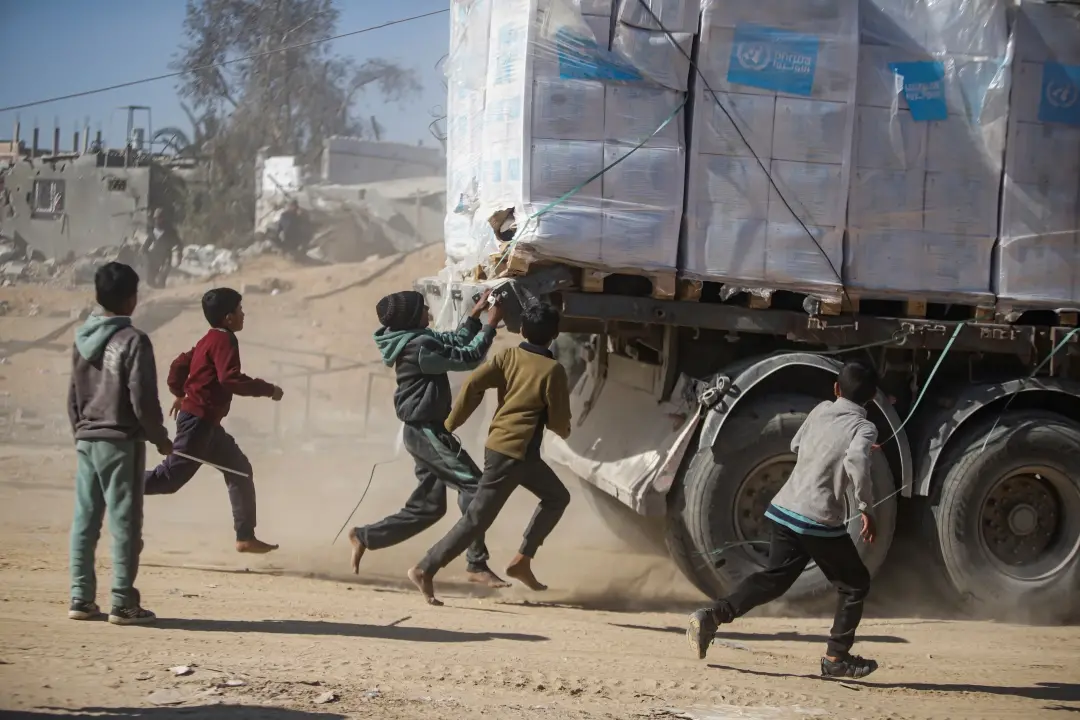 Palestinians chase humanitarian aid trucks that arrived through the Kerem Shalom crossing from Egypt into the Gaza Strip | Photo: AP