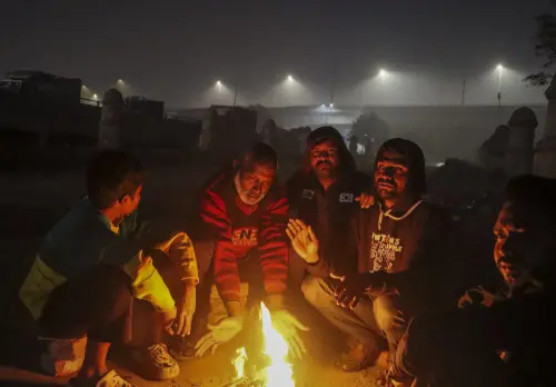 People sit around a bonfire to keep themselves warm on a cold winter evening, in New Delhi. | PTI