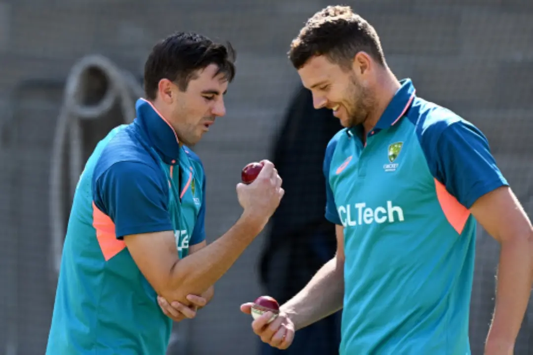 Australian captain Pat Cummins (L) rubs his elbow as teammate Josh Hazlewood (R) smiles in the nets | File Photo: AFP