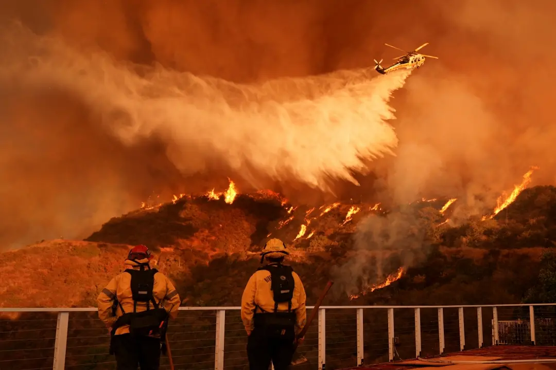 Firefighters watch as water is dropped on the Palisades Fire in Mandeville Canyon on Saturday