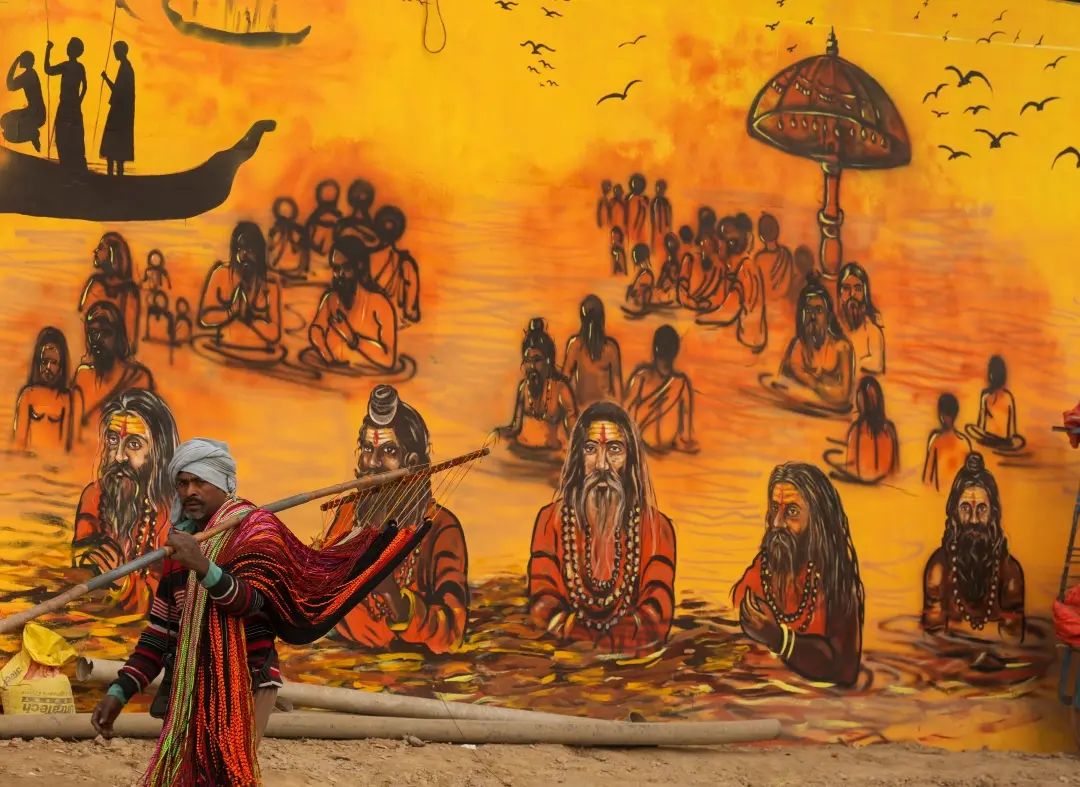A devotee walks past a mural ahead of Maha Kumbh Mela 2025, in Prayagraj, Uttar Pradesh | Photo: PTI