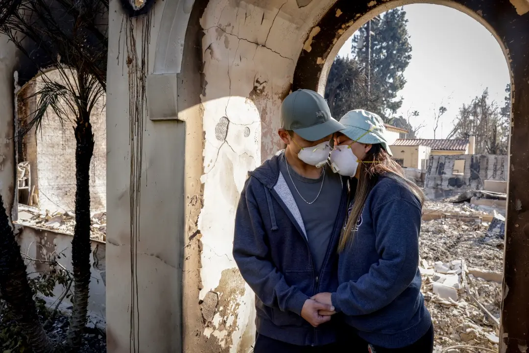 Gene Huang Lee, left, embraces his wife, Demmi Choo, outside their home destroyed by the Eaton Fire in Altadena in California | Photo: AP
