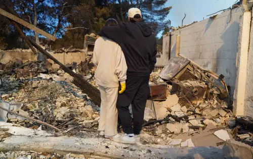People as they stand on the ruins of their house destroyed by the LA fire
