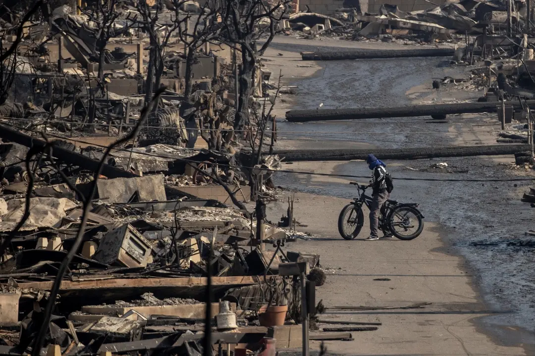A bicyclist stands amongst Pacific Palisades Bowl Mobile Estates destroyed by the Palisades Fire in Pacific Palisades, Calif | Photo: AP