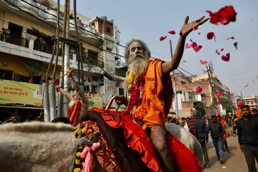 A Sadhu, or a Hindu holy man, throws flower petals on the devotees as he takes part in a religious procession of Niranjani Akhara | Photo: AFP