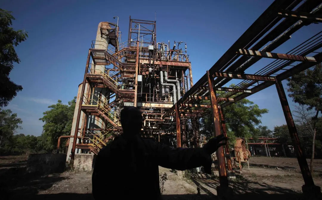 A security guard is silhouetted against defunct machinery at the Union Carbide pesticide plant