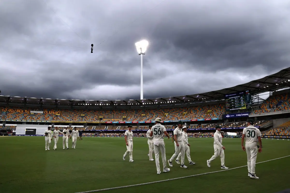 Australia's captain Pat Cummins (R) leads his team off the ground due to a rain delay on day five of the third cricket Test match between Australia and India at The Gabba in Brisbane | Photo: AFP