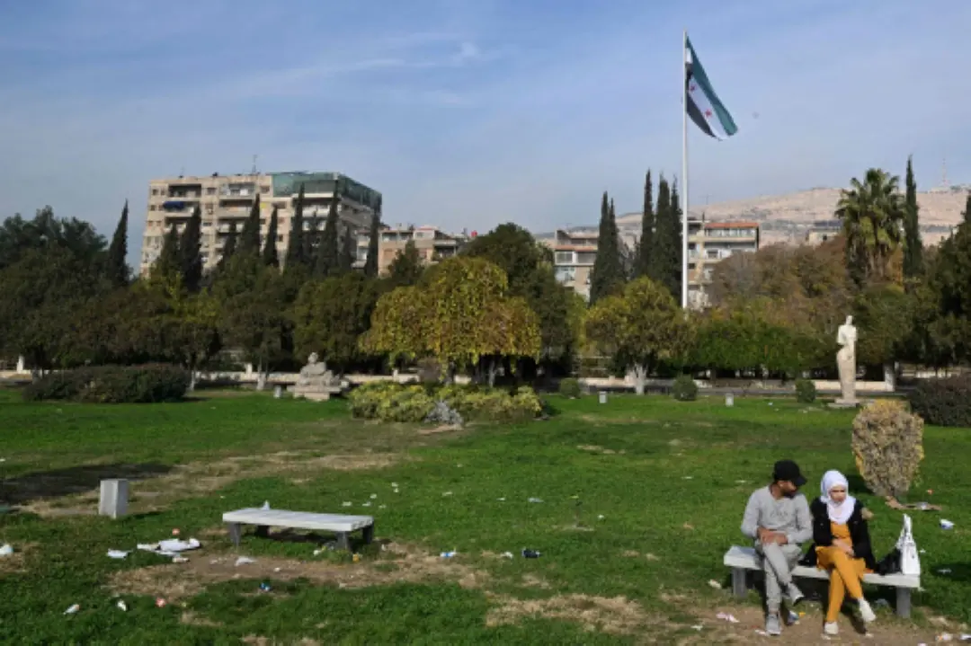 A couple sit on a bench in Damascus' central Umayyad Square.  In Damascus, life is cautiously returning to normal as residents step out of their homes into a Syria transformed by the ousting of long-time president Bashar al-Assad. | Photo: AFP