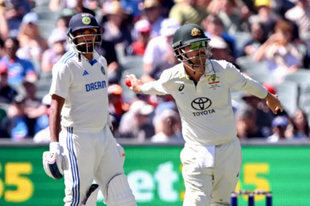 Australia's Travis Head (R) throws the ball as India's Mohammed Siraj looks on during the third day of the second cricket Test match between Australia and India at the Adelaide Oval. | Photo: AFP