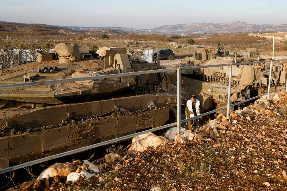An Israeli soldier walks past tanks deployed near the Israel-Syria border in the Israel-annexed Golan Heights | AFP