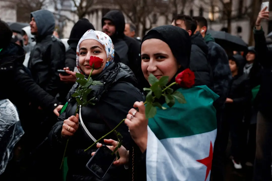 Demonstrators holding red roses as they take part in a gathering with other supporters and members of Syrian community and called by the Syria Solidarity Campaign group, in Trafalgar Square, central London, on Sunday, December 8, 2024, to celebrate the fall of the Assad regime.