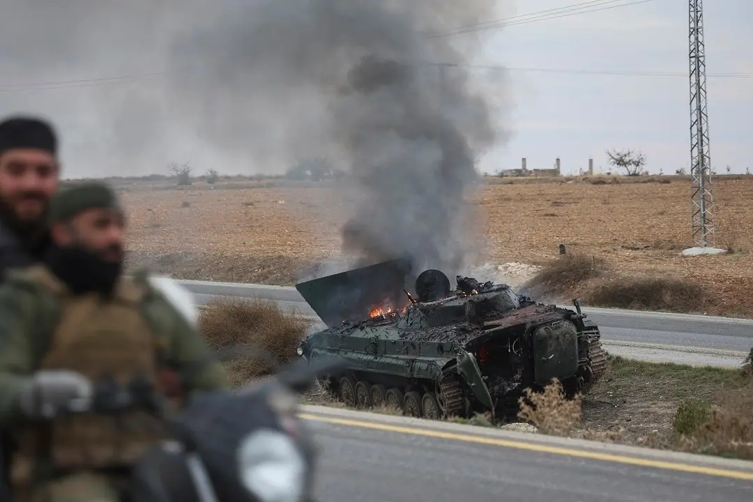 Syrian opposition fighters drive past a burning government armoured vehicle south of Hama, Syria | Photo: AP