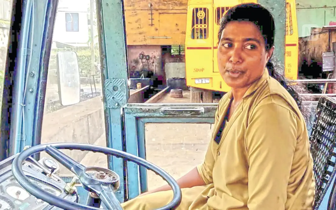 Rajani in the driving seat of the bus at the depot