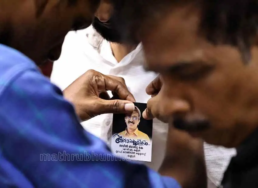 Colleagues mourn the death of ADM Naveen Babu by pinning his picture card on their clothes