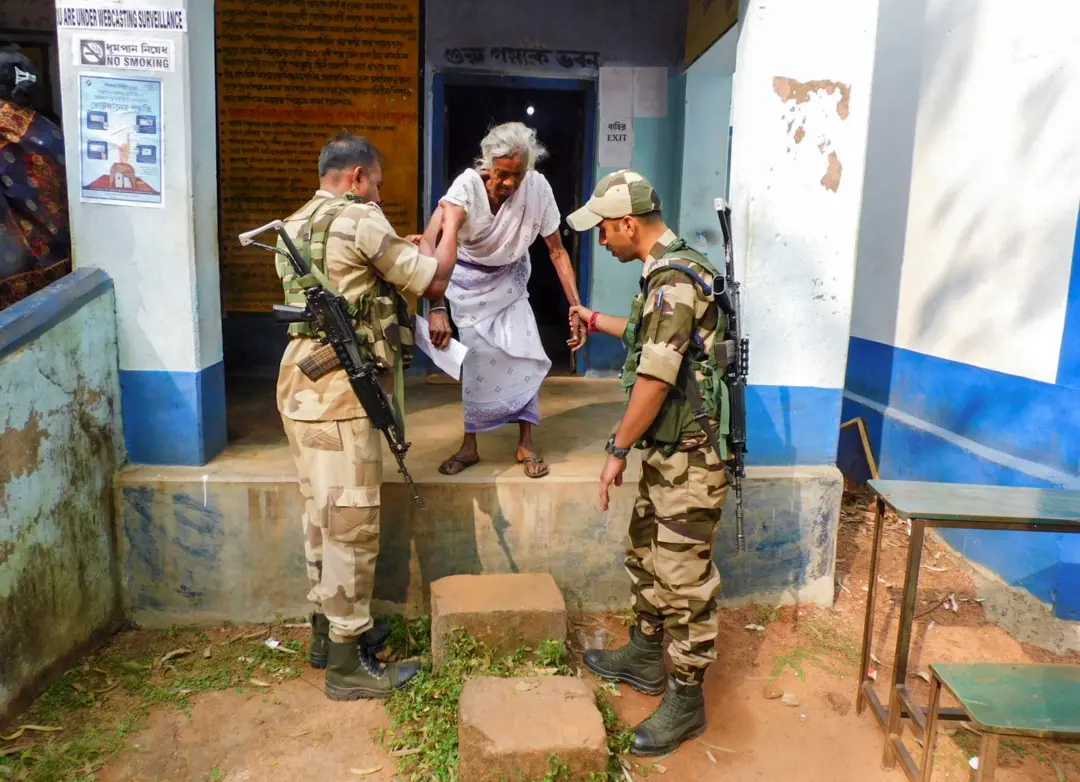 Security personnel assist an elderly woman during the by-election to Taldangra Assembly seat in Bankura district on Wednesday