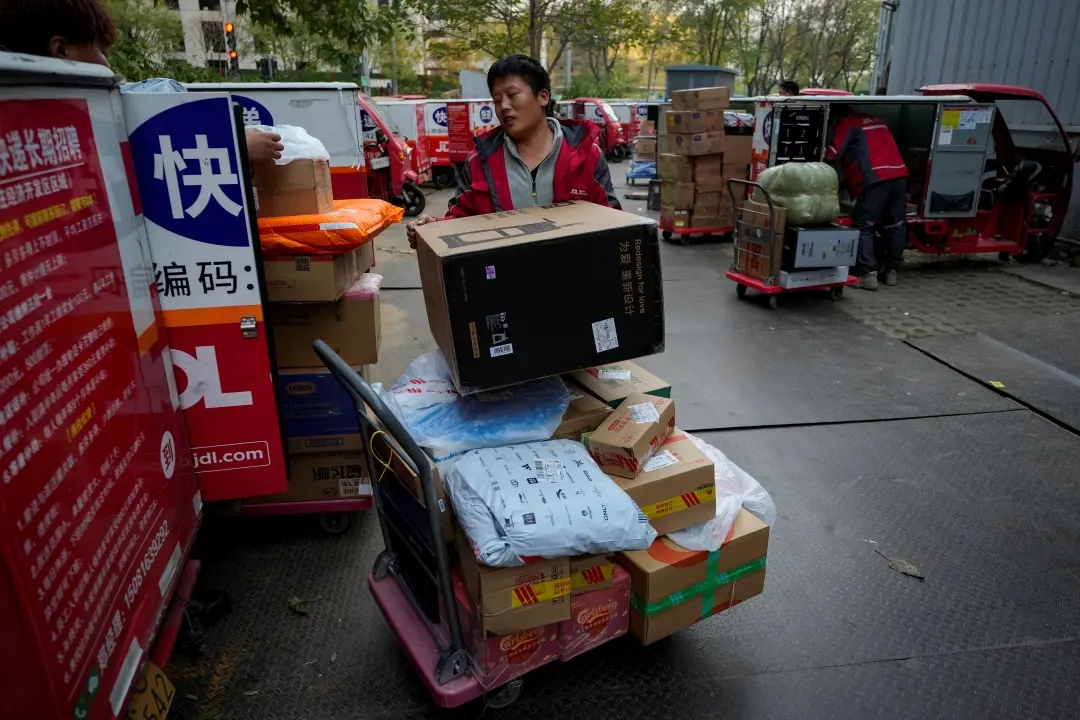 Delivery couriers sort out parcels for their customers at a distribution center for e-commerce platform JD.com on the occasion of Single's Day in Beijing on Monday