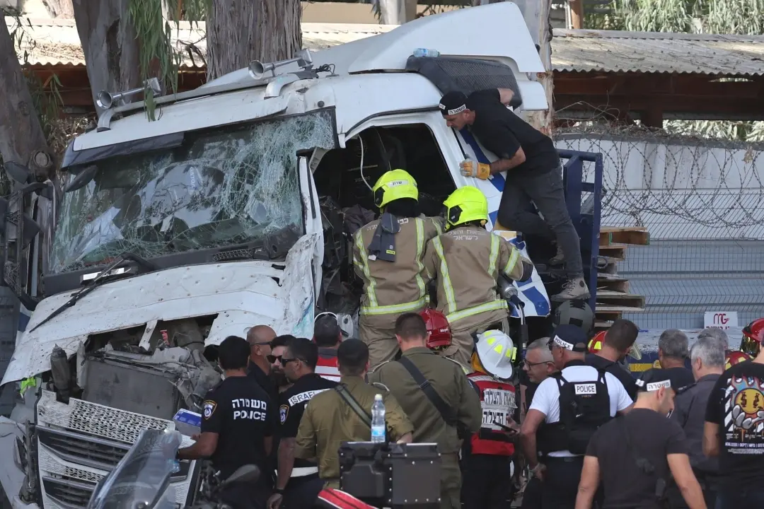 Israeli police and emergency responders recover the body of the truck driver at the site of a ramming attack in Ramat Hasharon, north of Tel Aviv | Photo: AFP