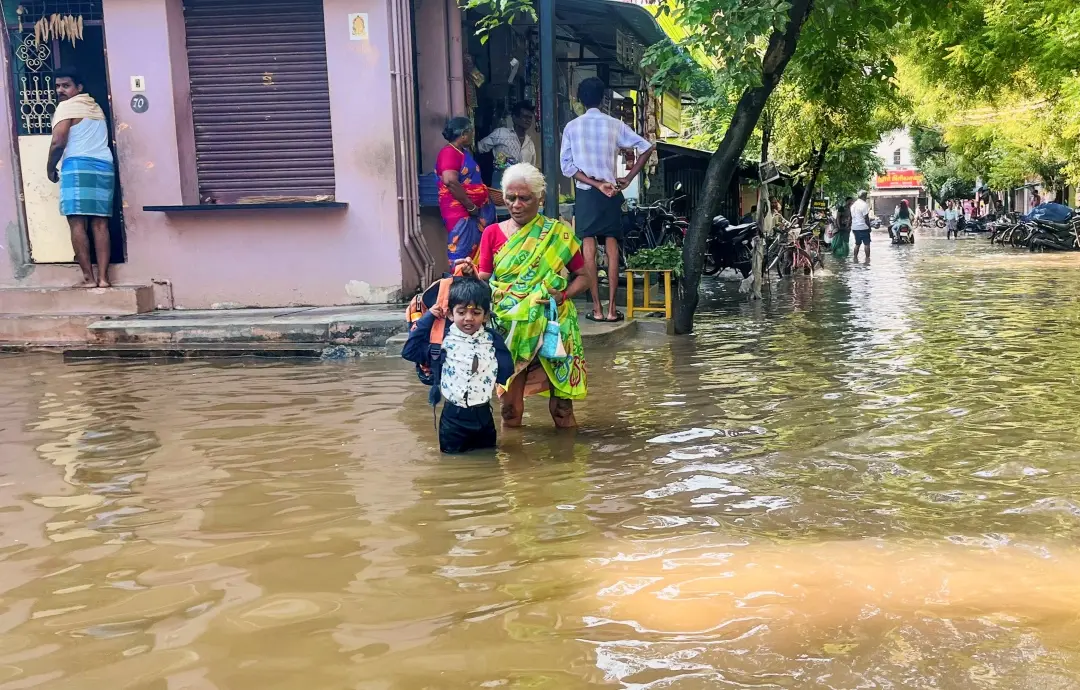 An elderly woman along with a child walks through a flooded area following the release of water from Anaiyur irrigation tank in Madurai | Photo: PTI