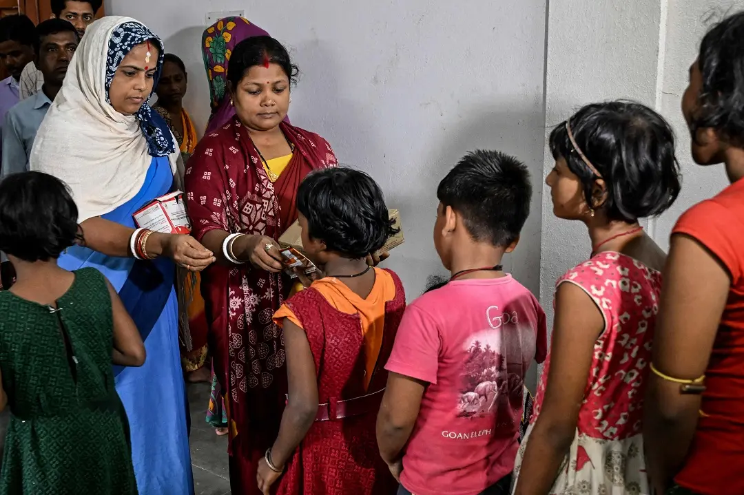 Children receive relief materials at a storm shelter before the landing of cyclone Dana, in Balasore district of Odisha | Photo: AFP