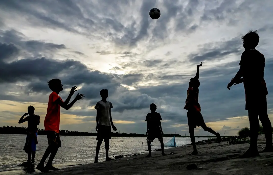 Boys at play at the bank of the Hooghly river under a cloudy sky | Photo: PTI