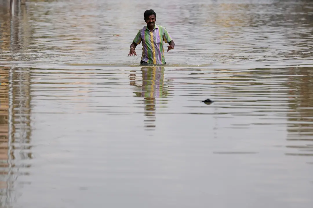 A man wades through a flooded street after heavy rains in Bengaluru | Photo: AP