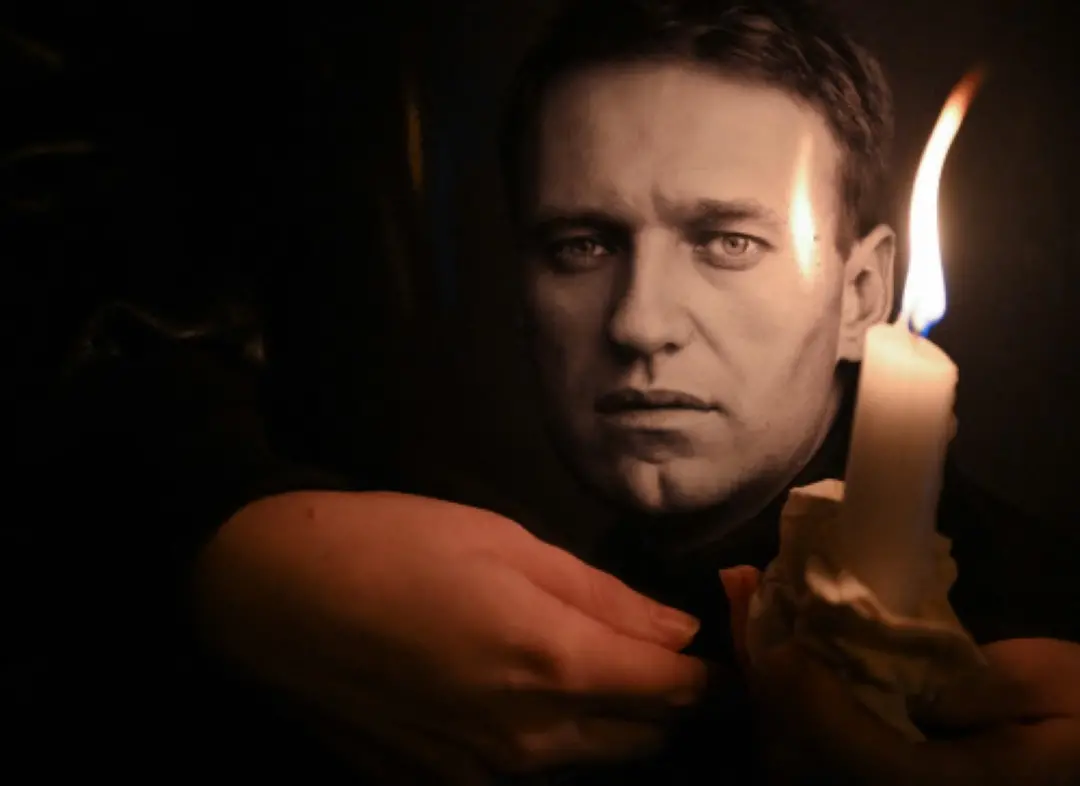 A man holds a candle and a photo of Russian opposition leader Alexei Navalny at a makeshift memorial as people demonstrate and pay their respect following his death in prison. | File Photo: AFP