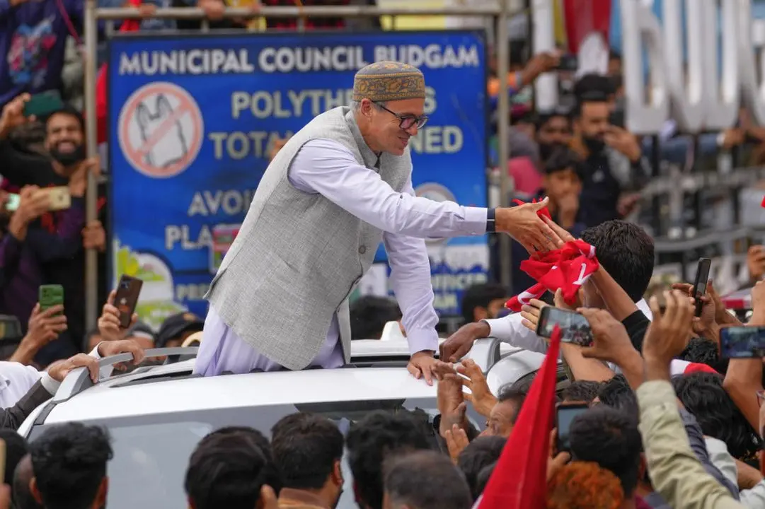 Jammu and Kashmir National Conference (JKNC) party leader Omar Abdullah, standing in car shakes hands with supporters as he celebrates his victory in Budgam