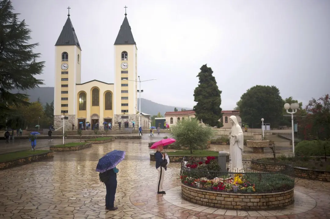 Pilgrims say their prayers next to the statue of the Virgin Mary in Medjugorje, Bosnia, Thursday