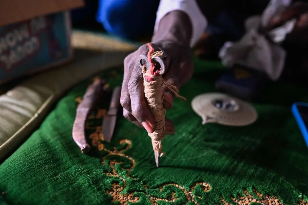 A person holds an excision instrument abandoned by former circumcisers in Touba, Ivory Coast | Photo:  AFP