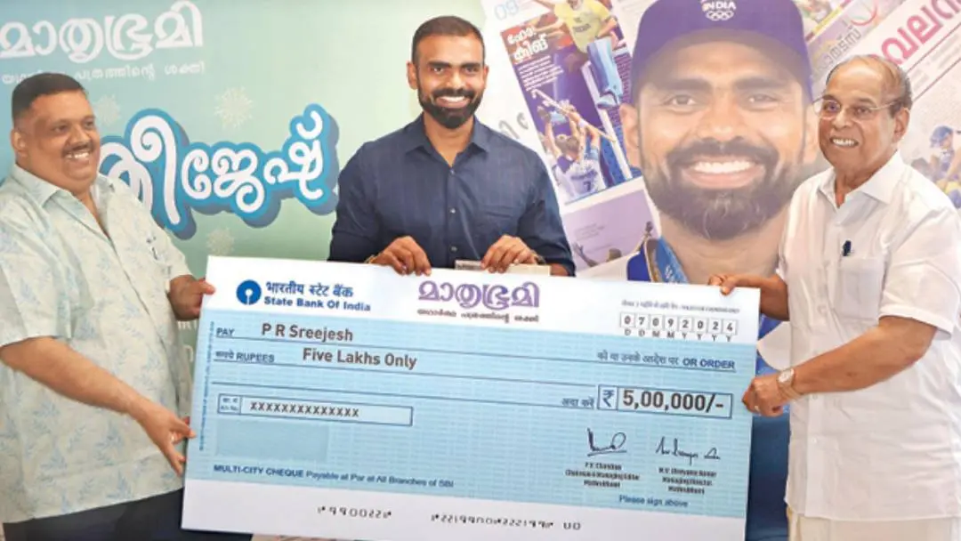 A cheque for Rs 5 lakh being handed over to PR Sreejesh by PV Chandran and KR Pramod at the Mathrubhumi head office in Kozhikode.