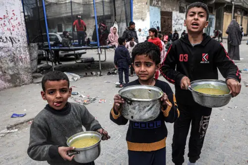 Boys stand holding pots filled with food provided by a charity organisation ahead of the fast-breaking 'iftar' meal during the Muslim holy month of Ramadan, in Rafah in the southern Gaza Strip amid the ongoing conflict in the Palestinian territory between Israel and the militant group Hamas. (Photo: AFP)