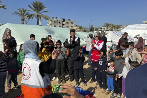 In this photo provided by IFRC, Kate Forbes, center, President of the International Federation of Red Cross and Red Crescent Societies (IFRC) visits the camp for the PRCS medical staff and their families in Rafah, Gaza, about 5 km in from the Rafah border crossing. (IFRC via AP)